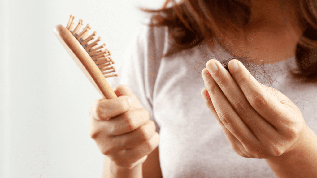 Girl holding comb and loss hairs.